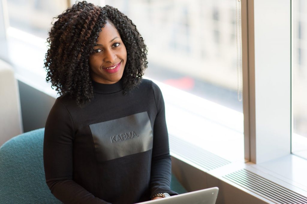 pexels photo 1181327 Black woman with curly hair working remotely indoors, exuding confidence and style.